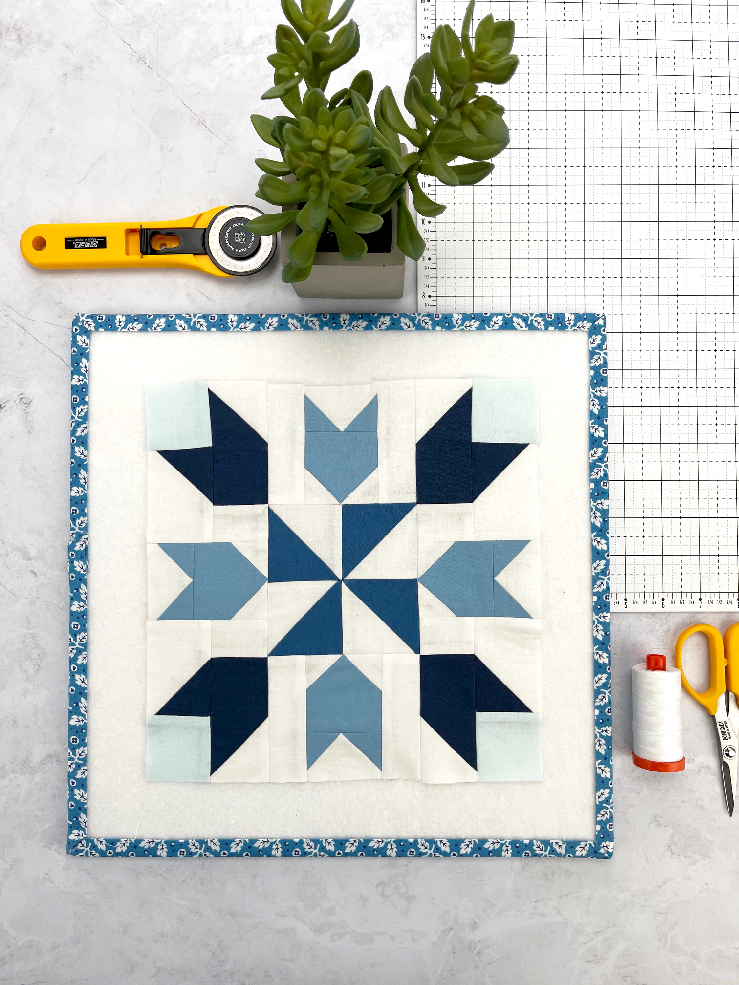 blauw en wit geometrisch quiltblok op witte tafel met naaiideeën