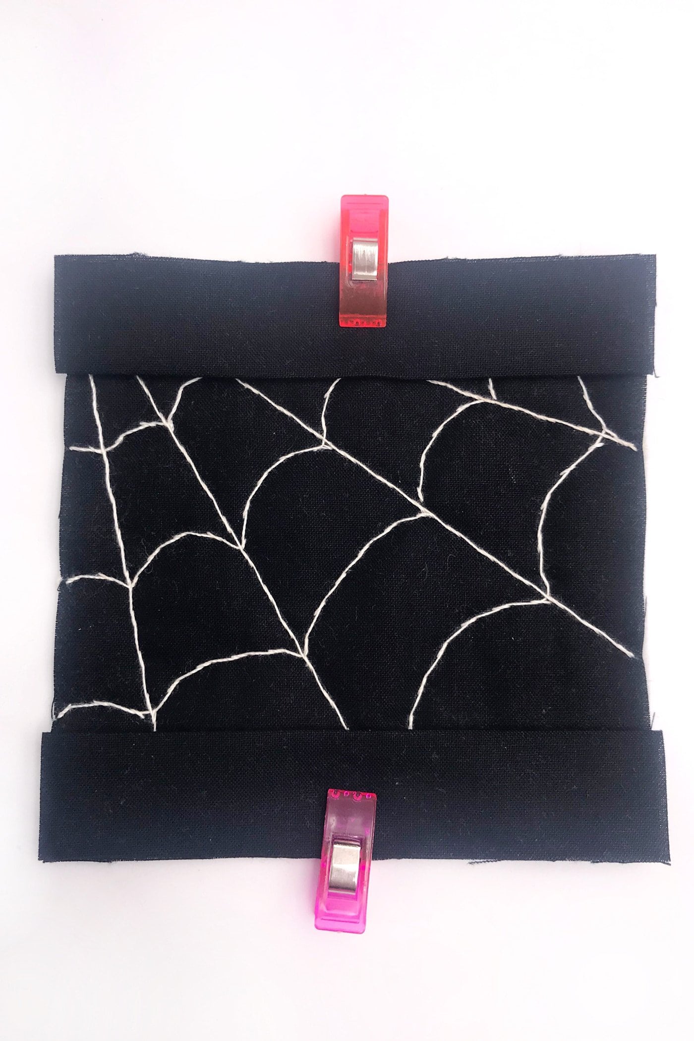 tissu noir avec une toile d'araignée blanche cousue avec du fil blanc sur une table blanche