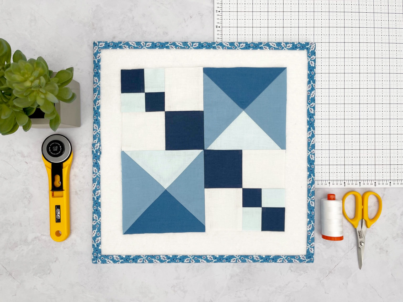 bloc de courtepointe graphique bleu et blanc sur tapis de découpe blanc avec des notions de couture