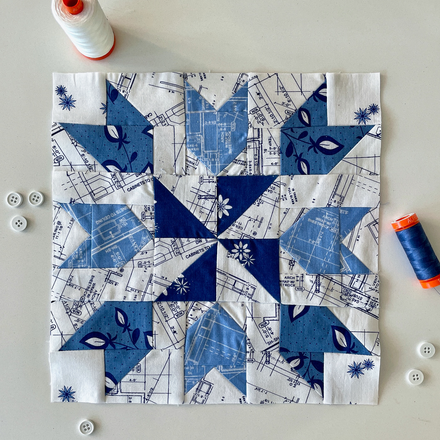 blauw en wit geometrisch quiltblok op witte tafel met naaiideeën