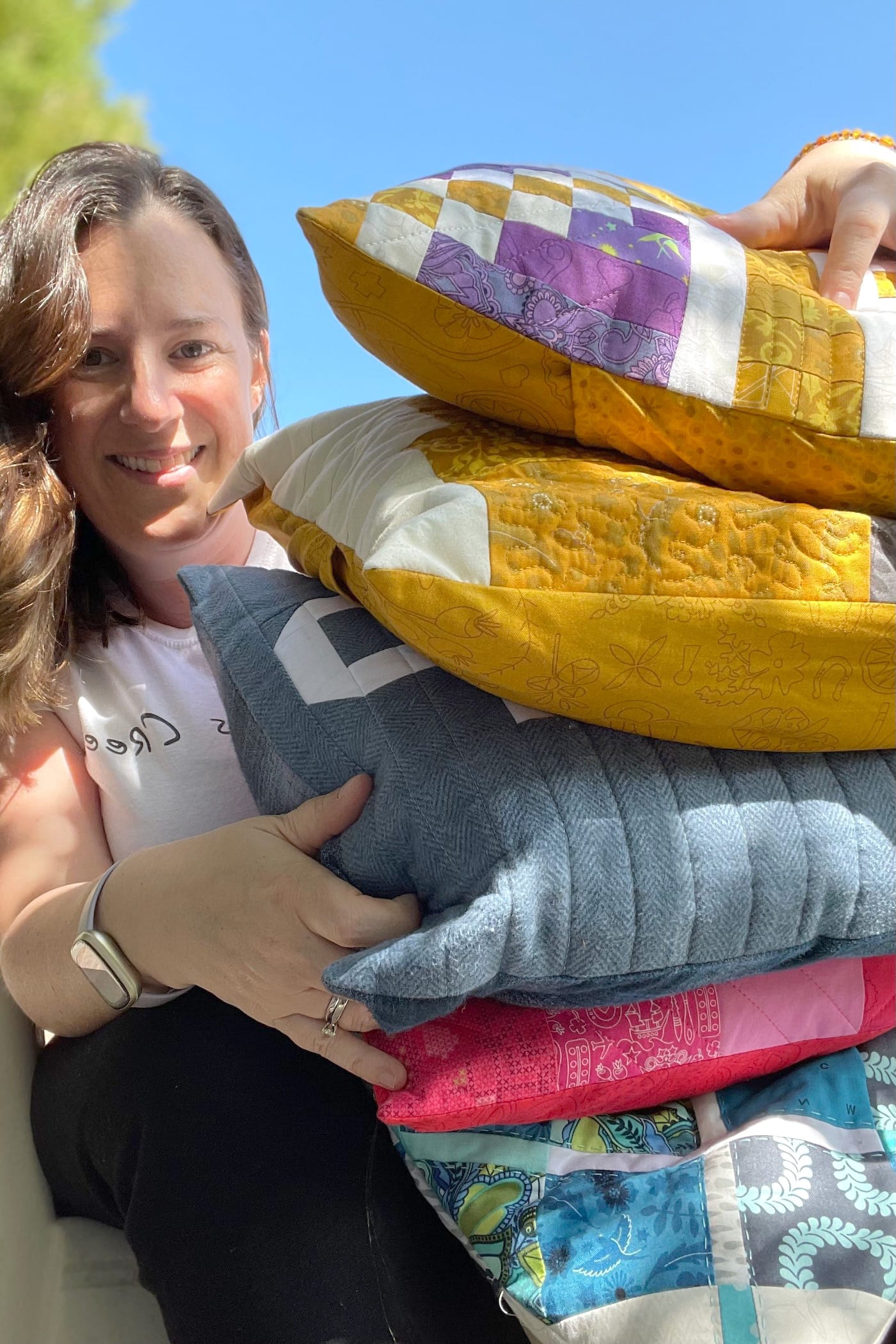femme tenant plusieurs oreillers patchwork colorés