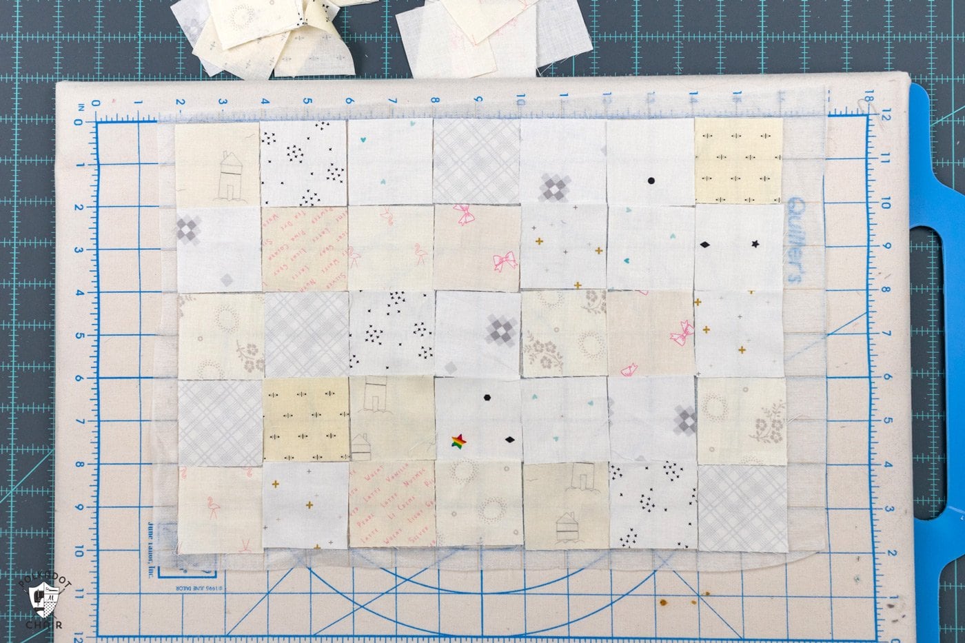 carrés de tissu crème et blancs disposés sur une planche à découper portable