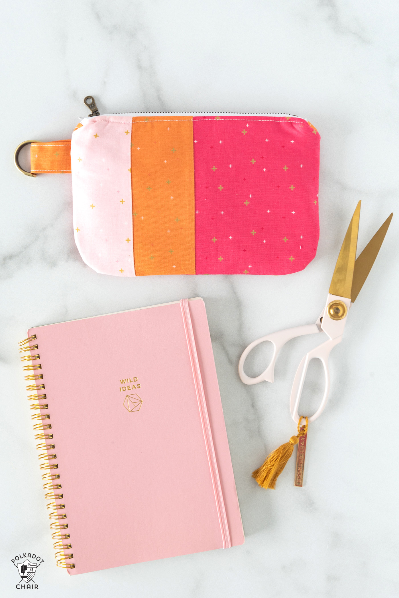 Pochette zippée rose et orange sur carnet avec stylos