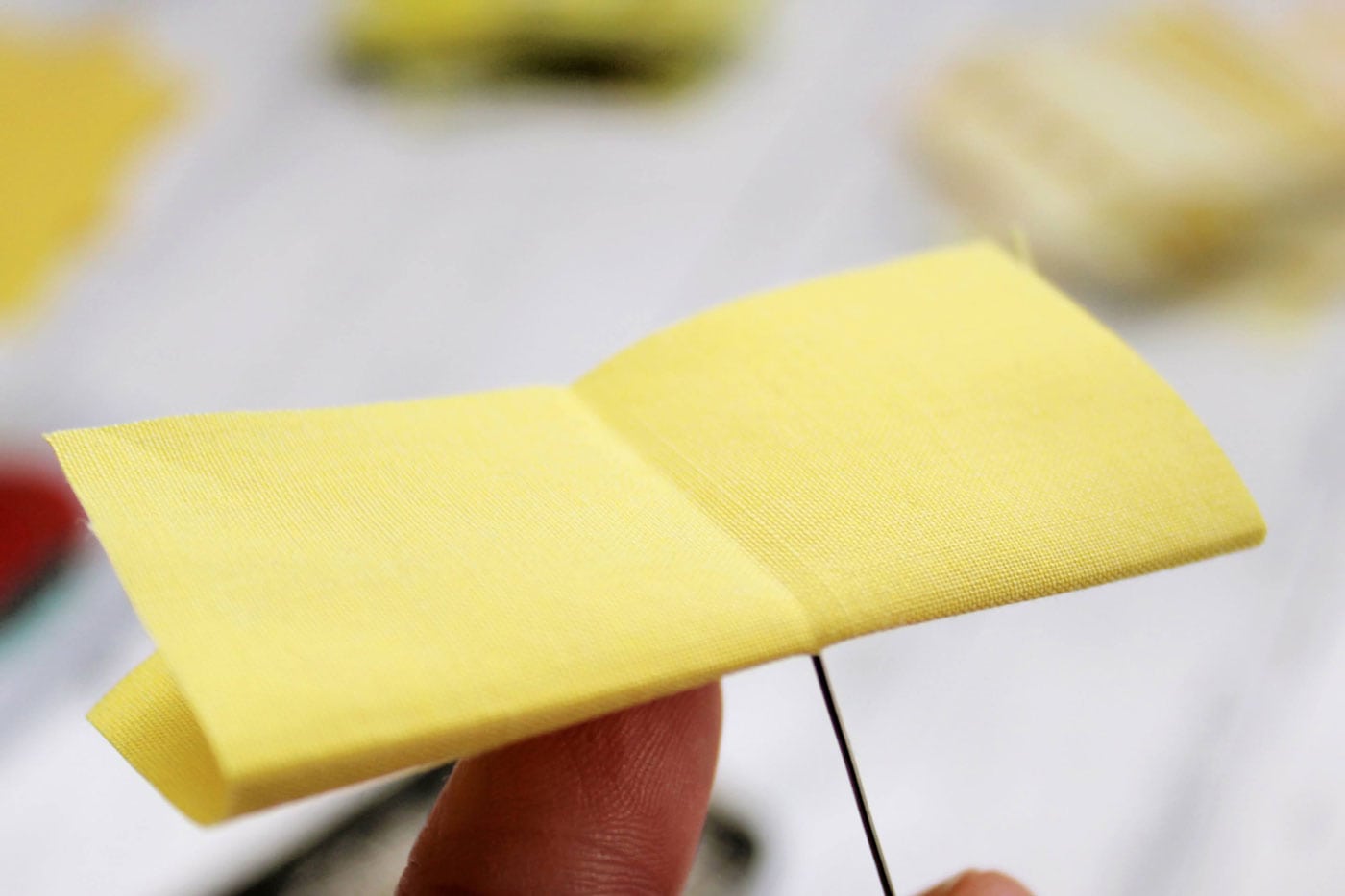 tissu jaune avec des plis, une épingle et une boule de polystyrène blanche