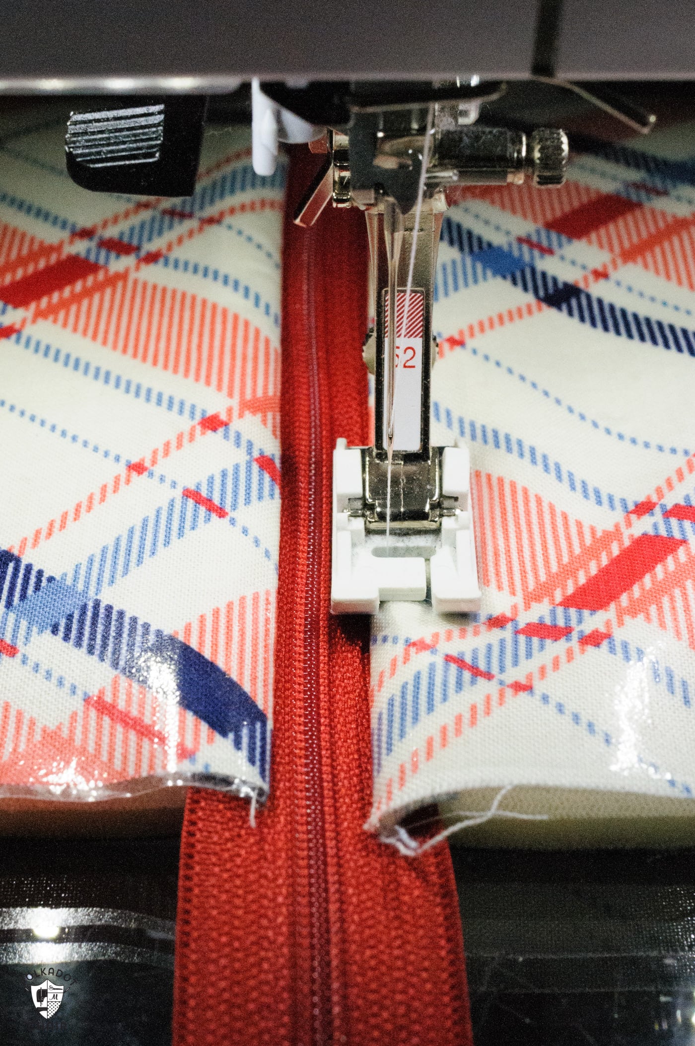 Pied-de-biche en téflon sur machine à coudre, tissu laminé rouge et bleu