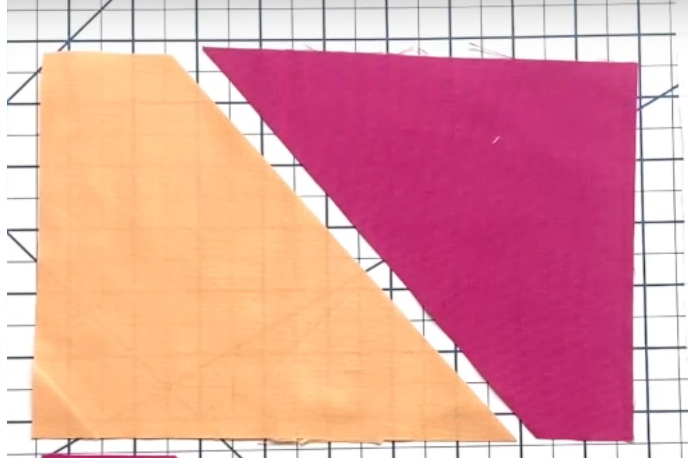 deux triangles de tissu coloré sur un tapis de découpe blanc