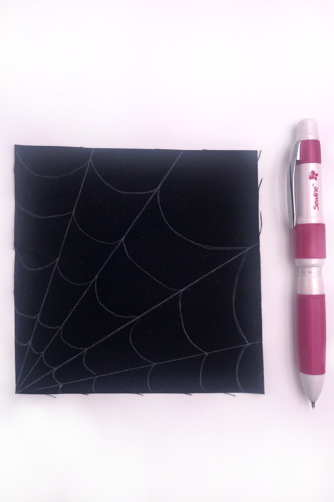 kain hitam dengan jaring laba-laba putih dijahit dengan benang putih di atas meja putih
