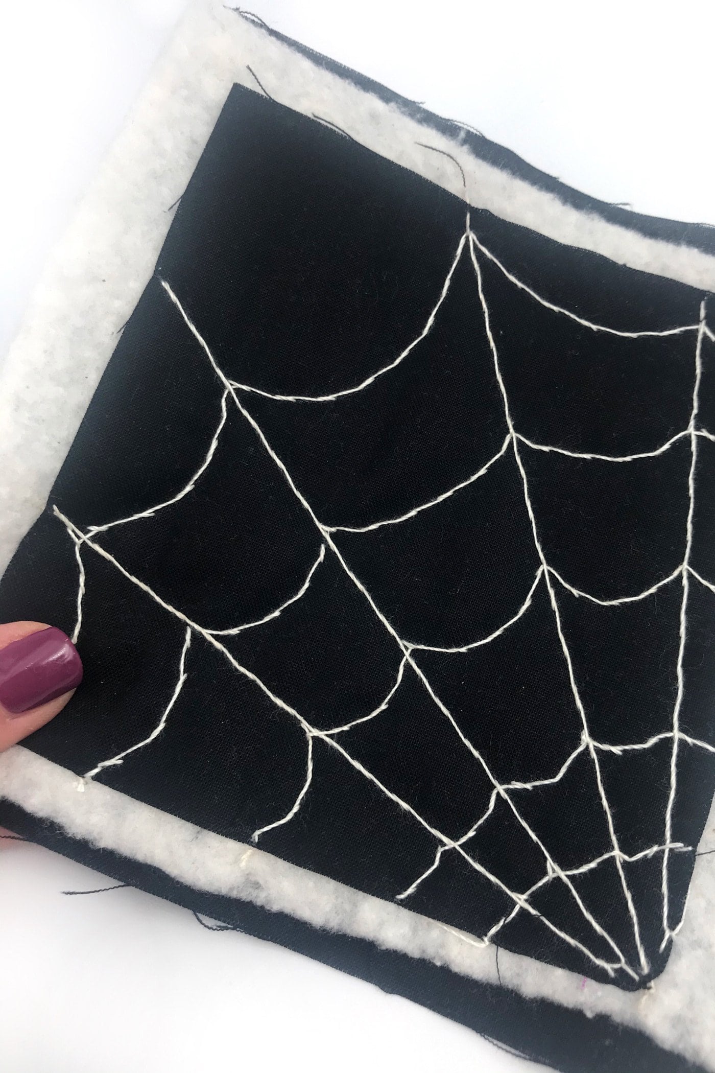 kain hitam dengan jaring laba-laba putih dijahit dengan benang putih di atas meja putih