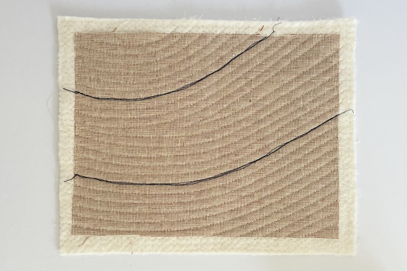 tissu beige sur table blanche avec des lignes cousues et matelassées