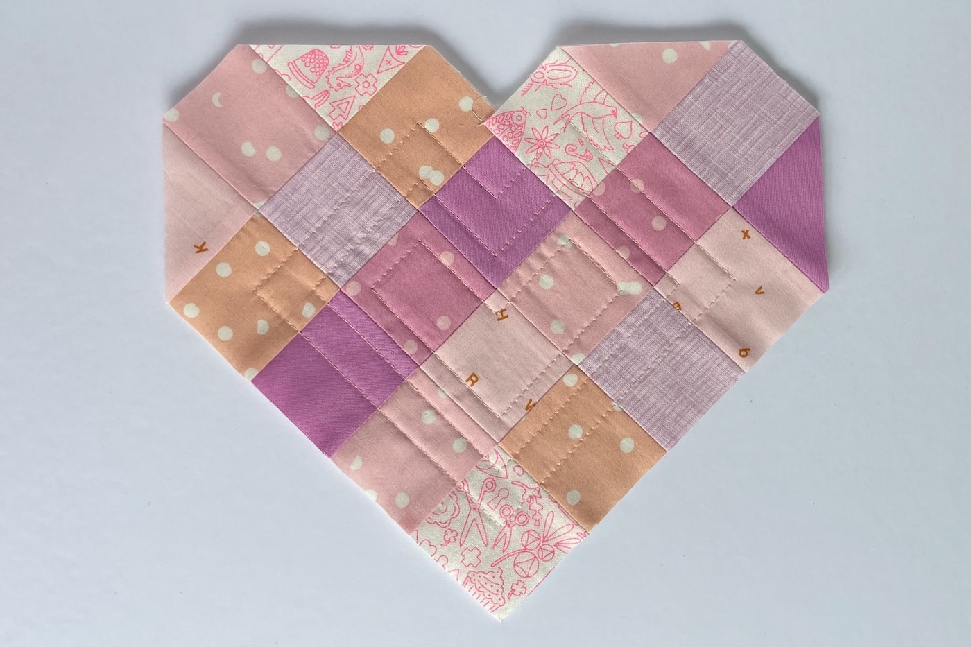 carrés de tissu rose cousus ensemble sur une table blanche