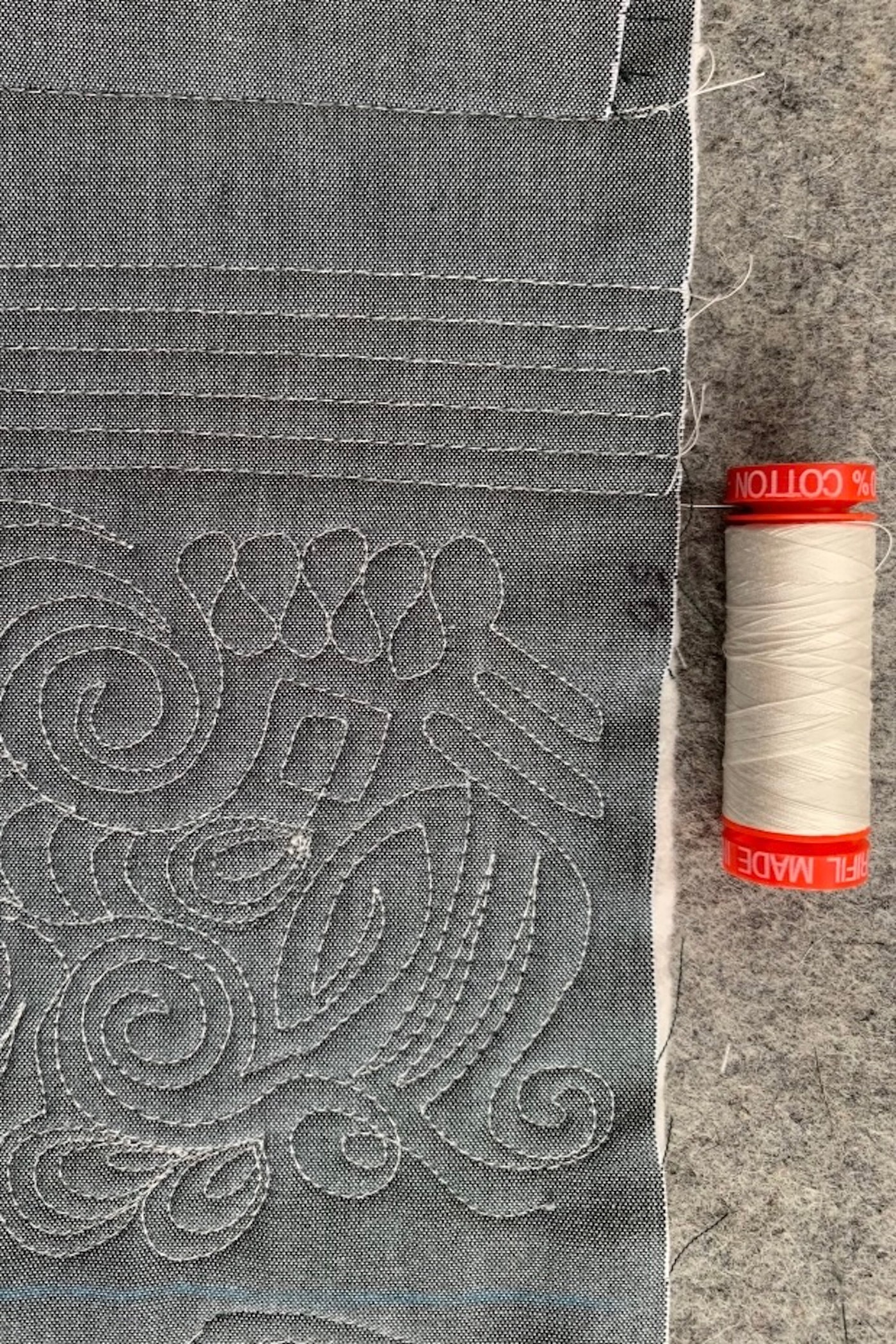 gros plan de fil ivoire sur tissu gris, matelassé à la machine
