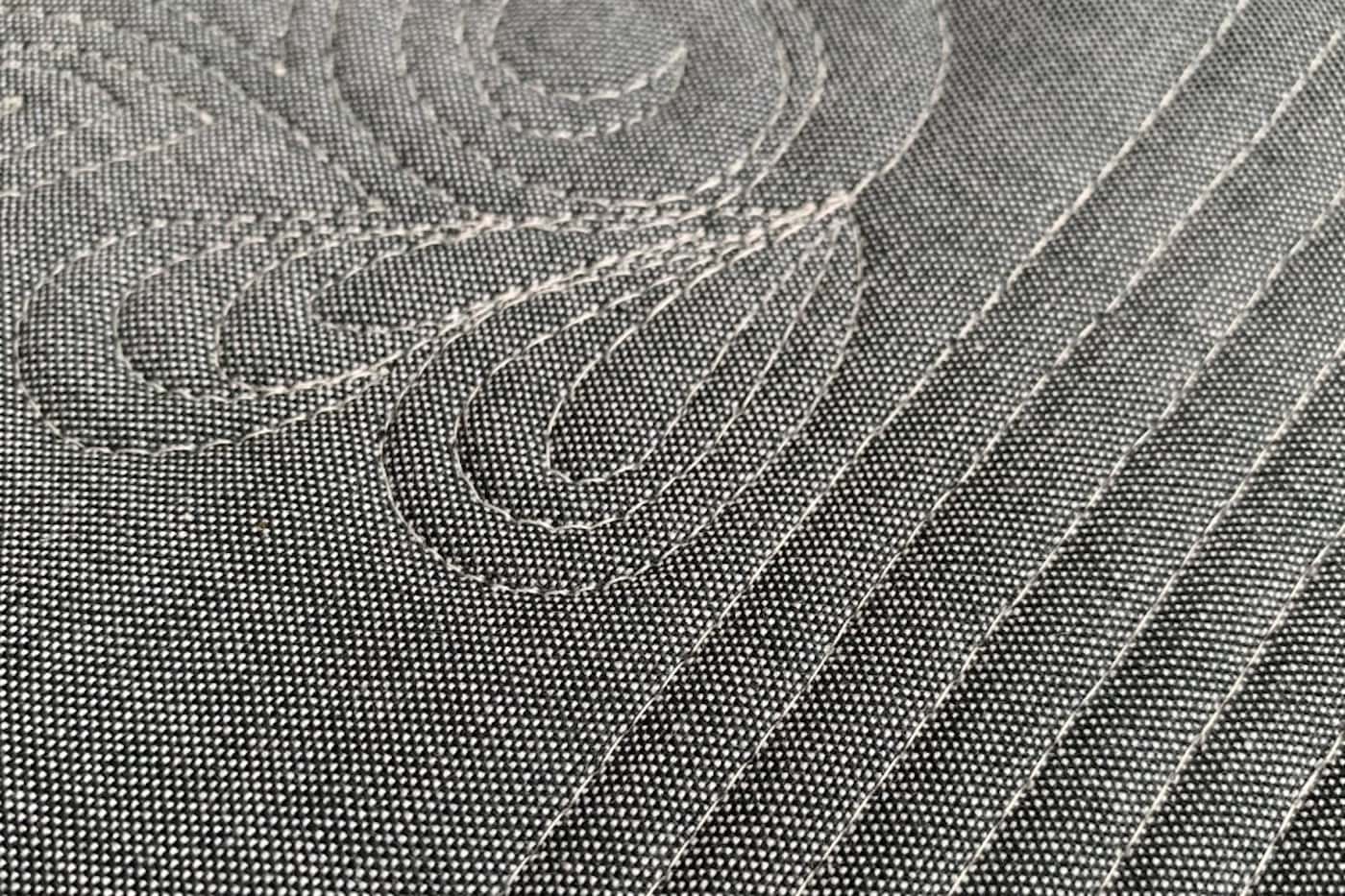 gros plan de fil ivoire sur tissu gris, matelassé à la machine