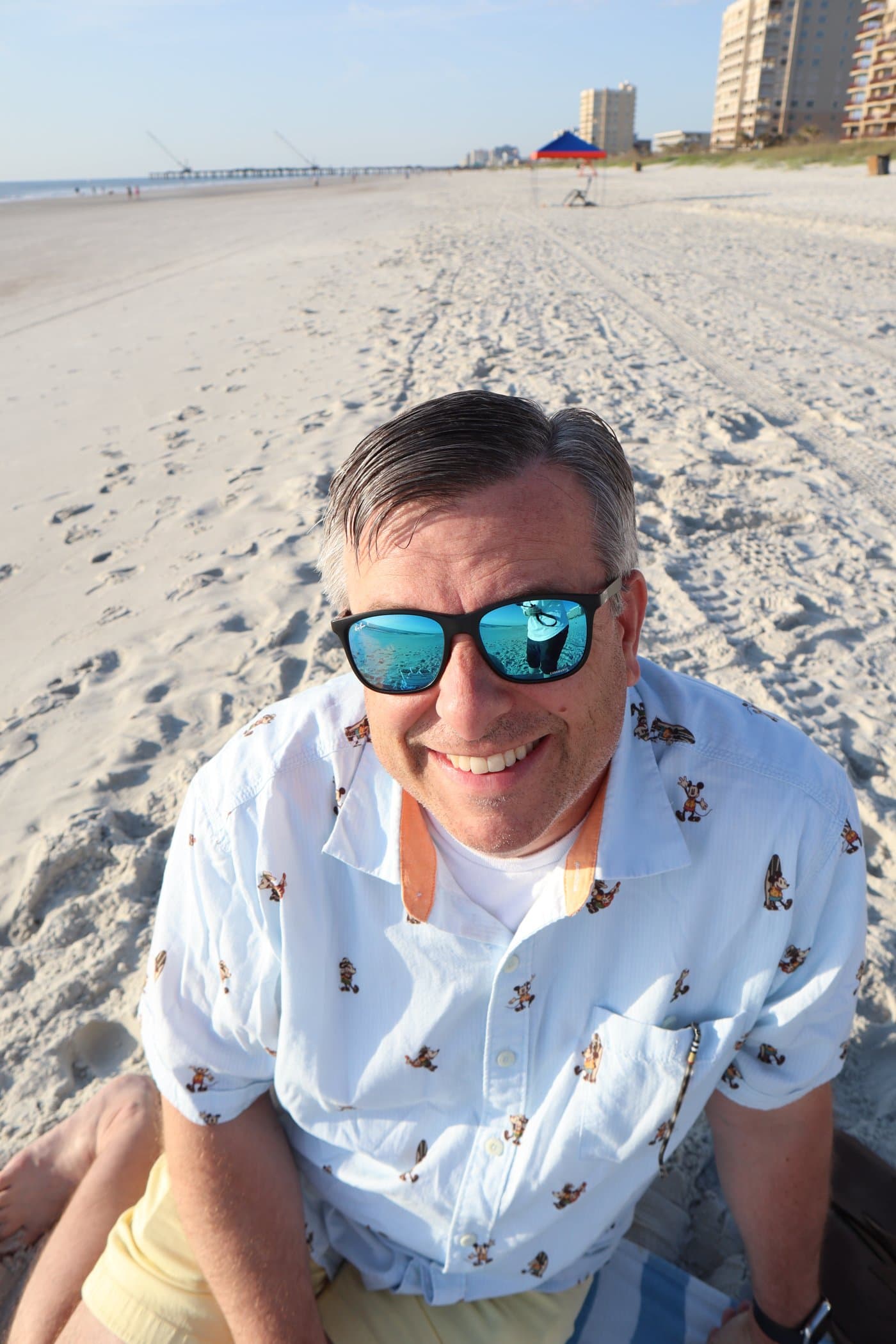 homme assis sur la plage portant des lunettes de soleil