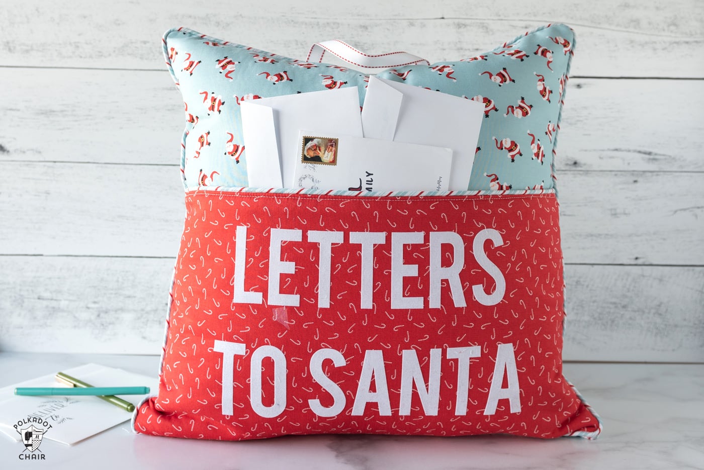 coussin de lecture rouge et turquoise sur fond blanc avec lettrage « lettres au père Noël » sur le devant