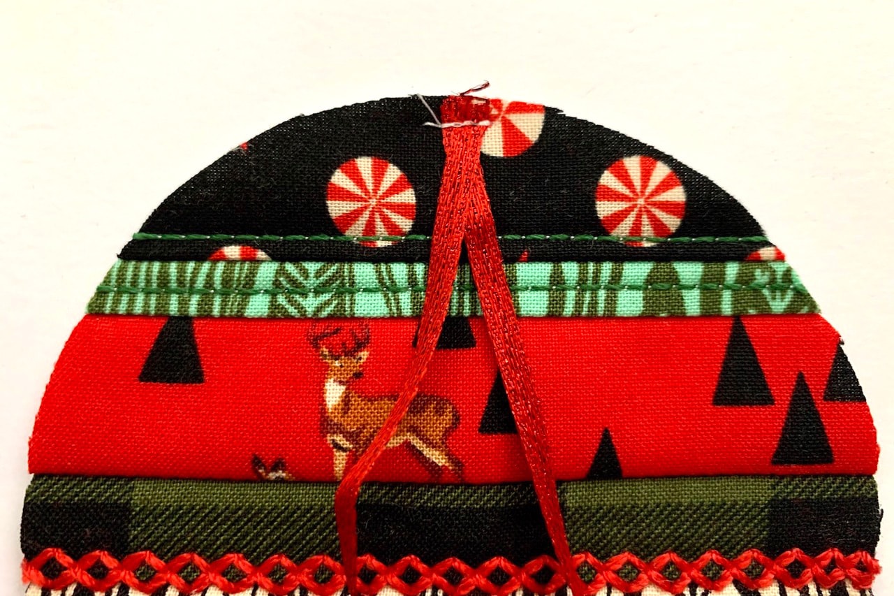 décoration de Noël rouge, verte et noire en construction avec ouate sur table blanche