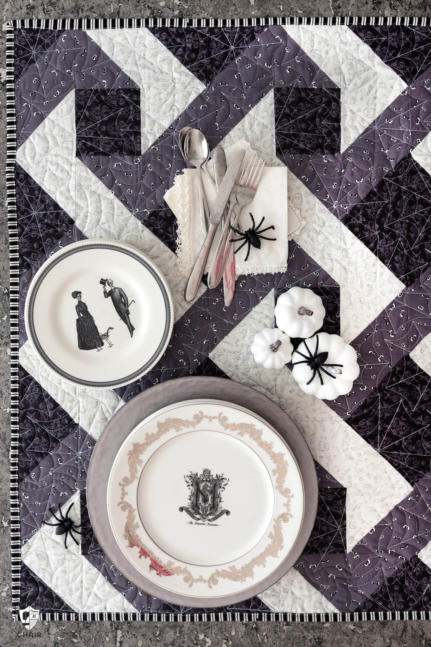 Table d'Halloween avec dessus de table matelassé gris et noir et assiettes blanches