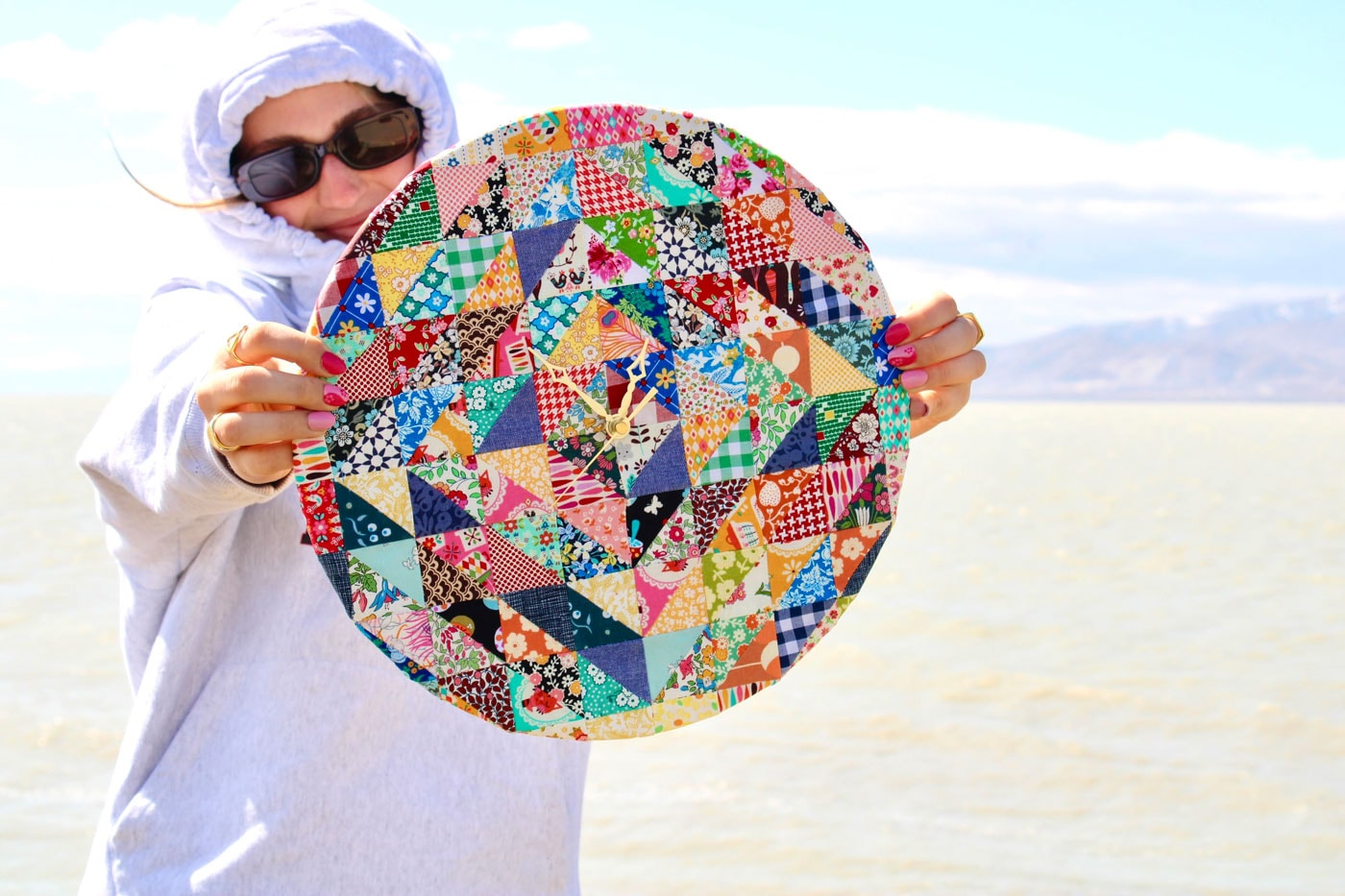 femme tenant une horloge patchwork à l'extérieur