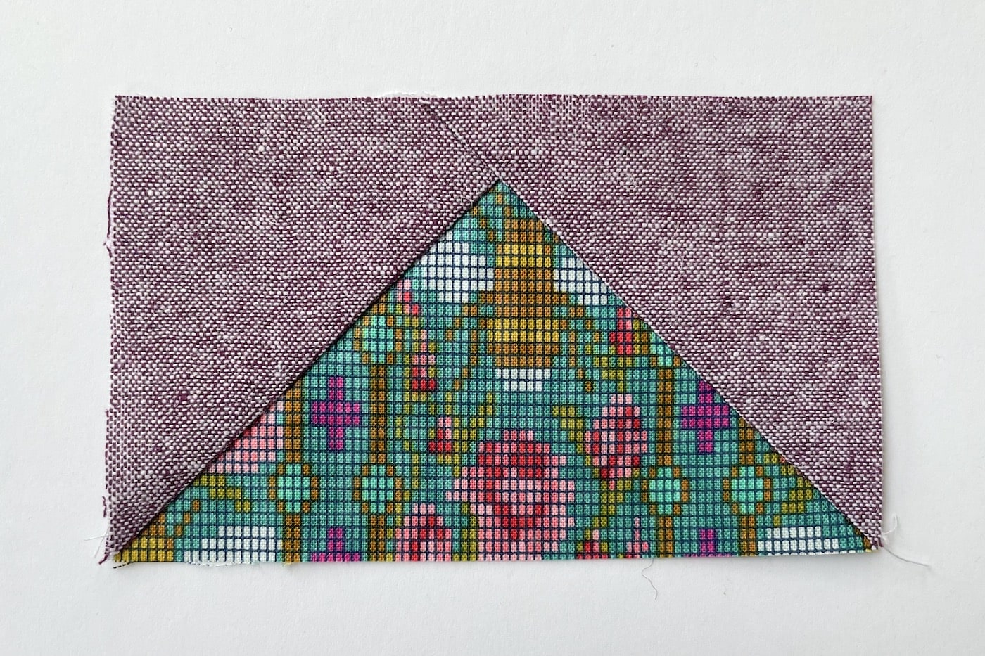 tissu violet et vert sur table blanche découpé en carrés et triangles
