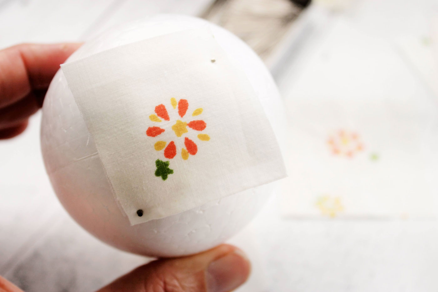 tissu blanc avec une fleur, un tissu plié jaune et une boule de polystyrène à différentes étapes de construction