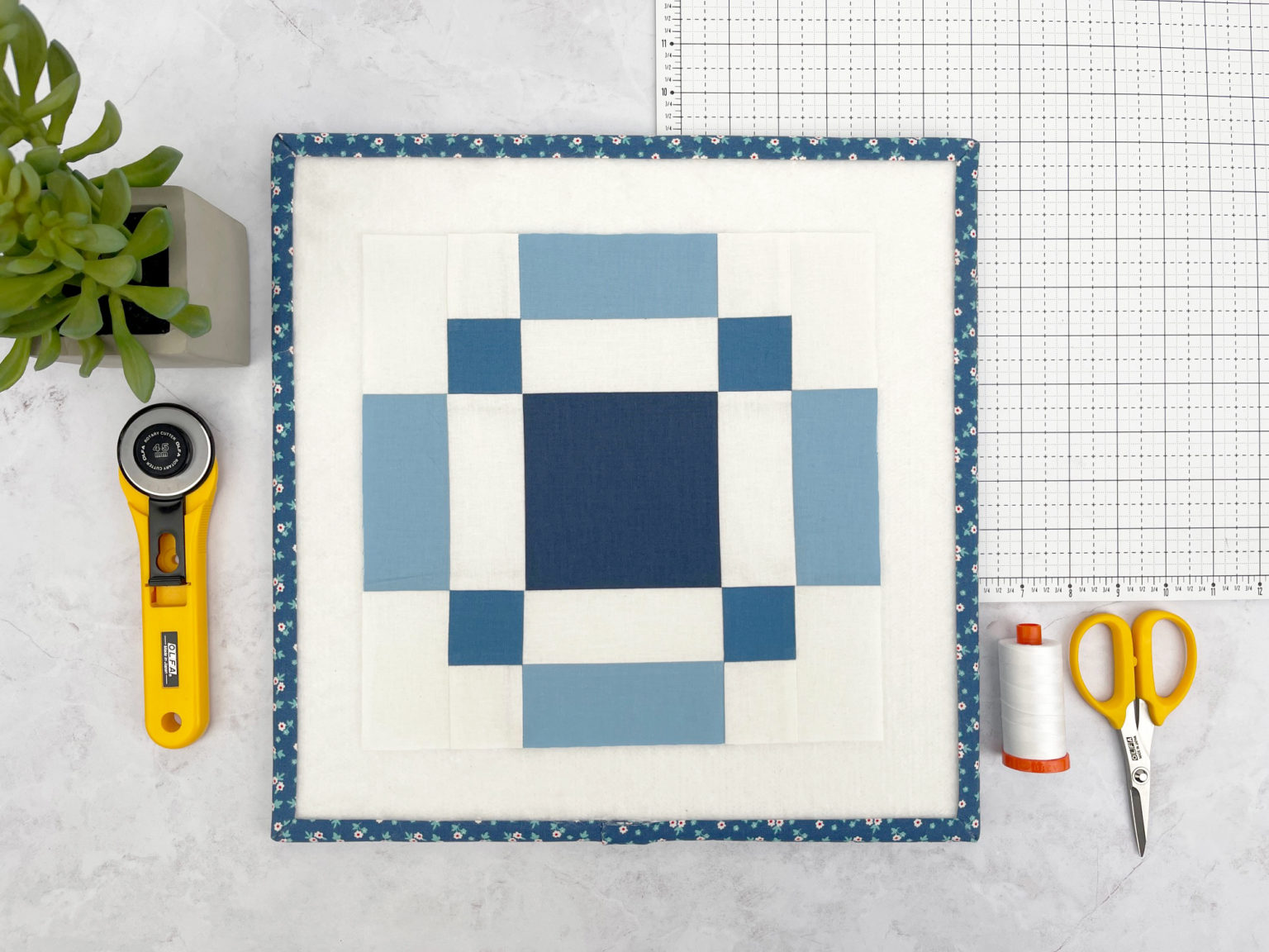 Blauw-wit quiltblok met naaiideeën op een witte snijmat