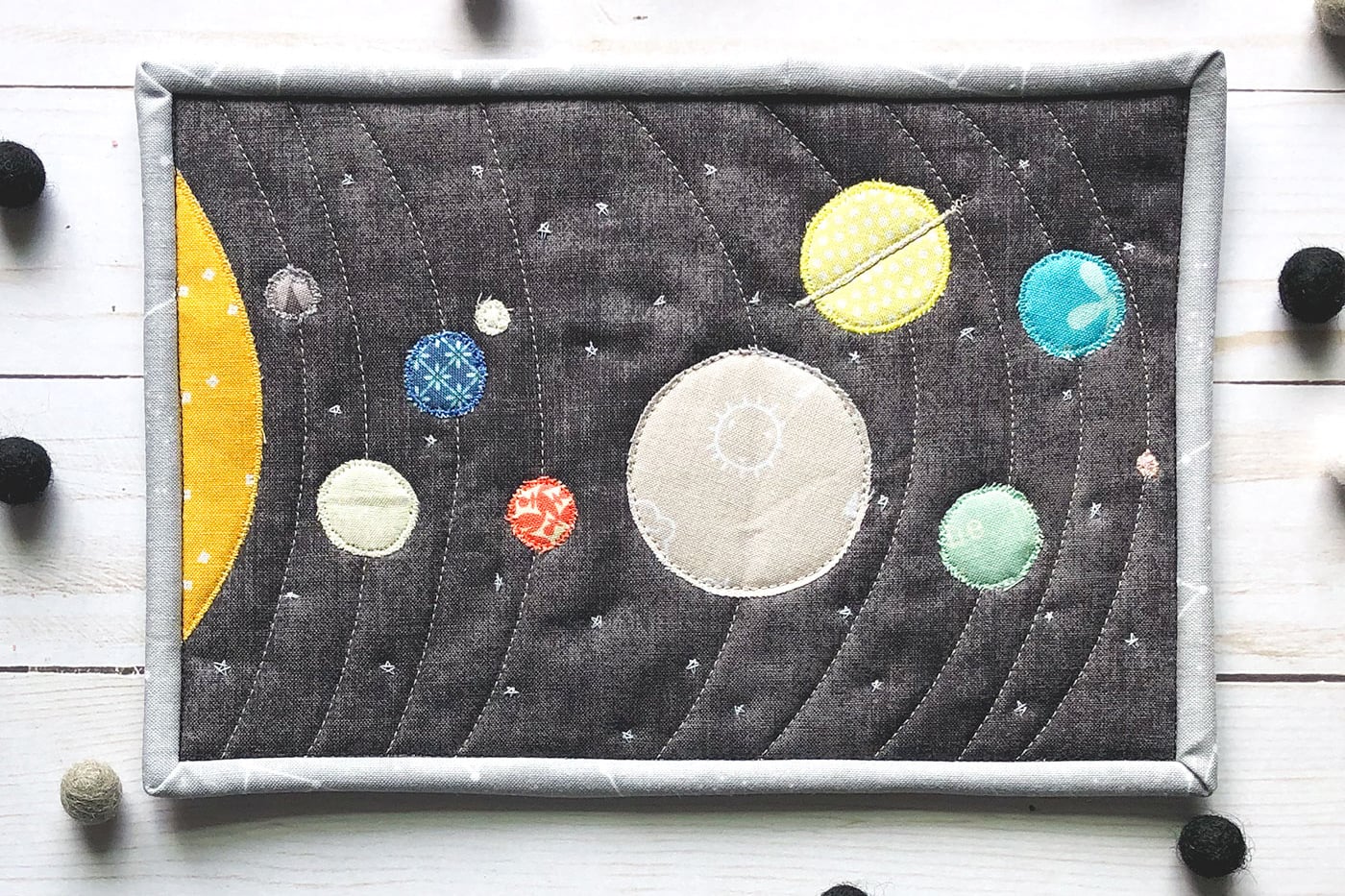 Tapis mug en tissu coloré du système solaire sur une table en bois blanc