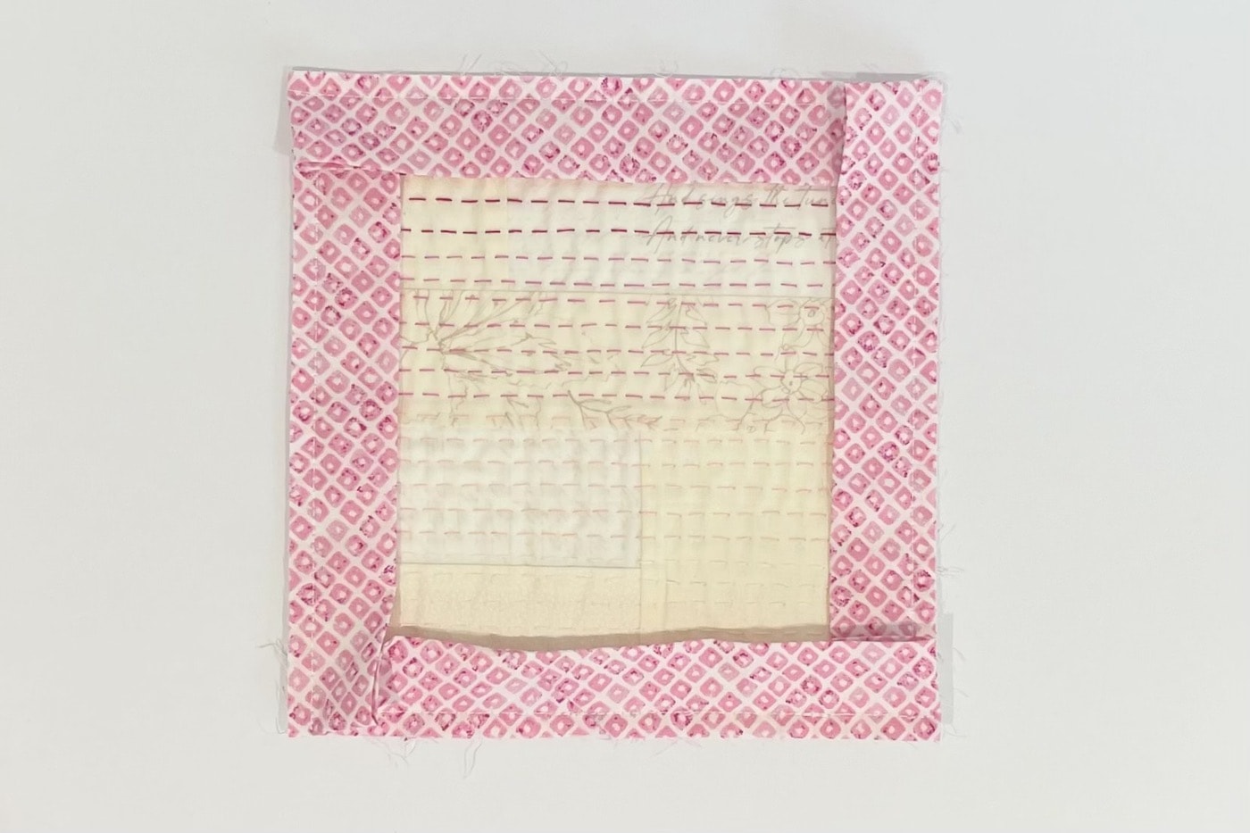 gros plan de tissus crème cousus ensemble sur une table blanche avec des coutures à la main roses et un tissu à bordure rose